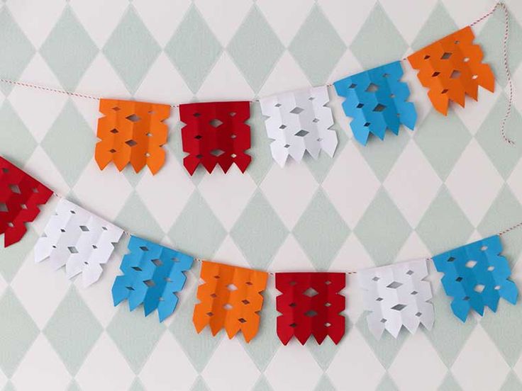 paper garland with red, white and blue fish cut outs hanging on a string in front of a checkered wall