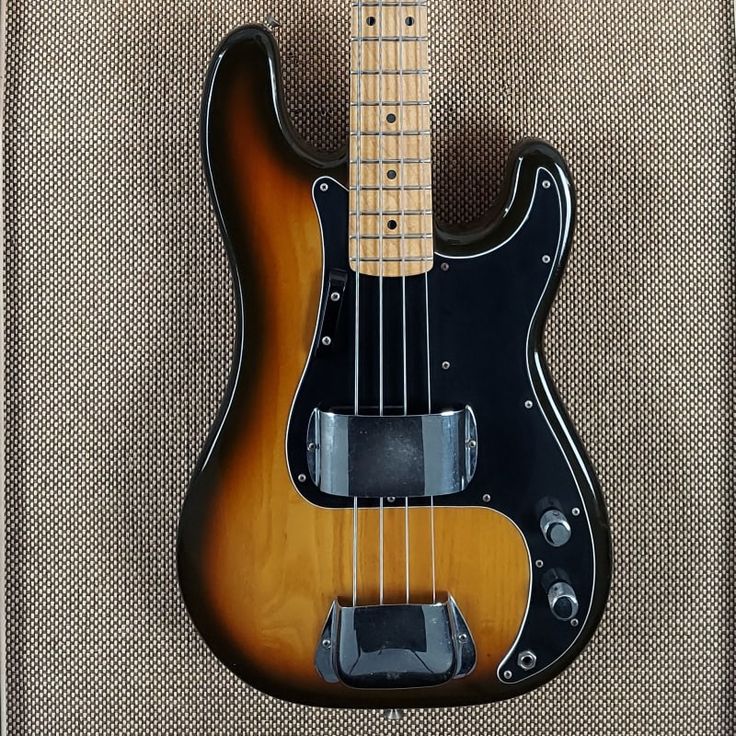 an electric bass guitar sitting on top of a carpeted floor next to a wall