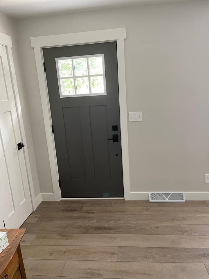 an empty room with a gray door and wood flooring on the side walk way