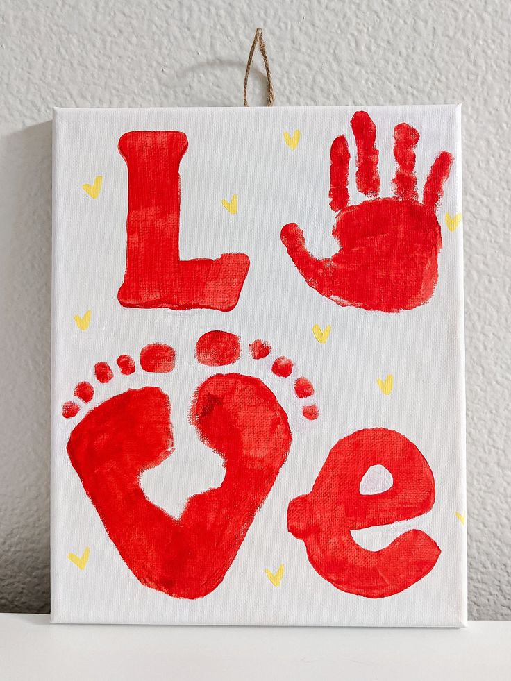 a hand and foot print on a canvas with the word love written in red ink