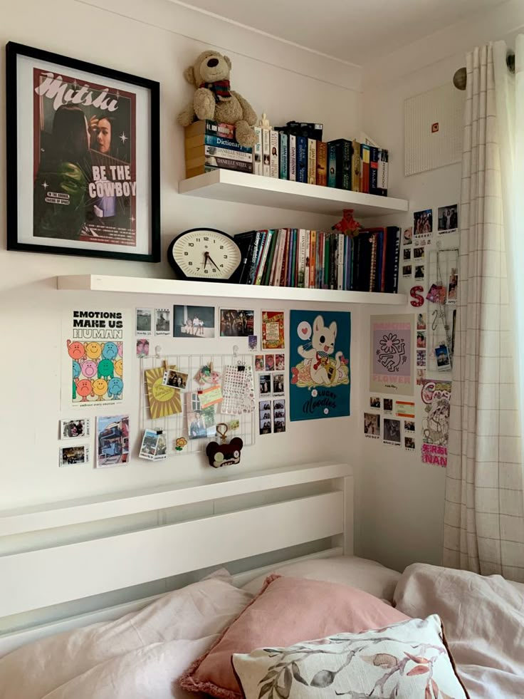 a bedroom with bookshelves and pictures on the wall above the bed, along with a teddy bear