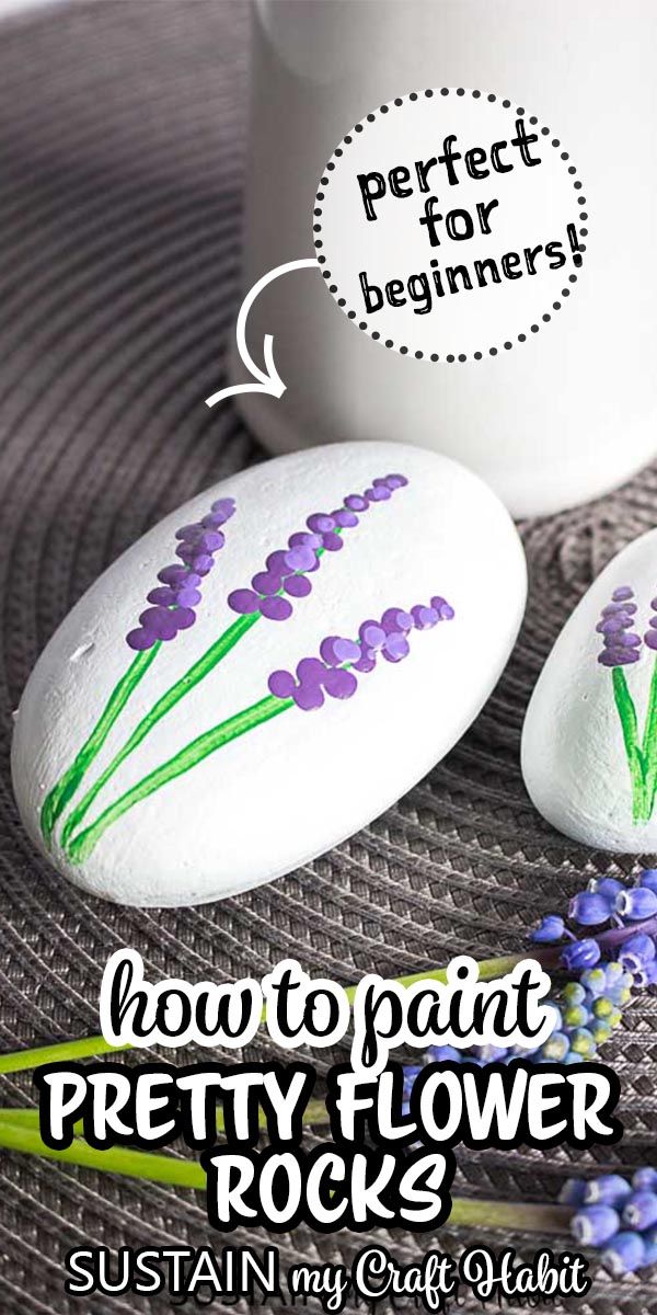 some rocks with flowers painted on them next to a cup