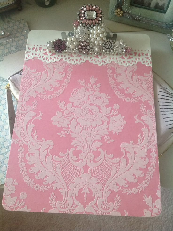 a pink and white damask paper on a desk with other items in the background