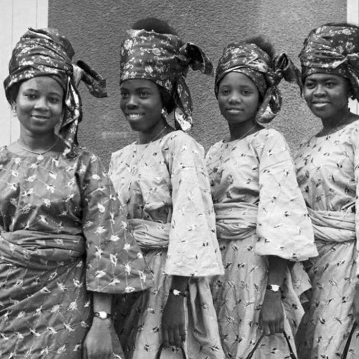 an old photo of four women in traditional african garb and head wraps, standing next to each other