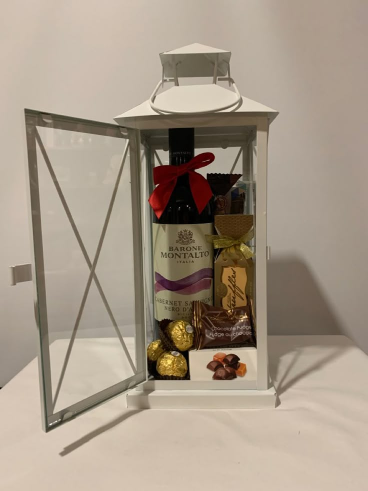 a bottle of wine and some chocolates in a glass box with a bow on top