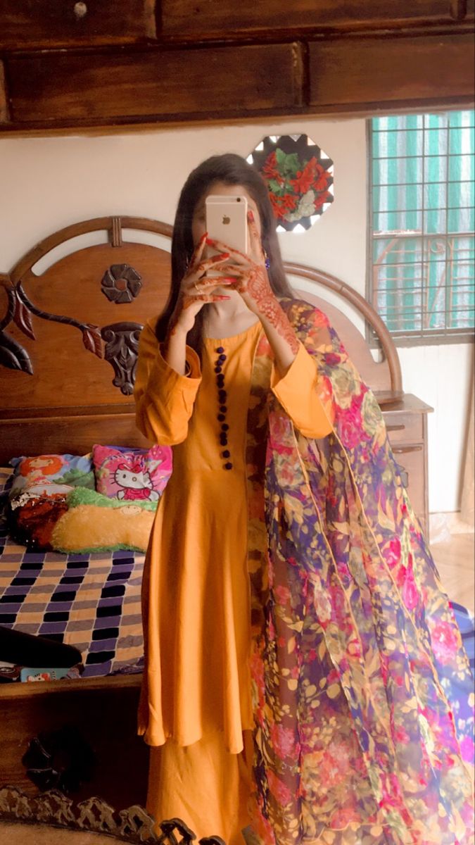 a woman taking a selfie with her cell phone in front of an ornate bed