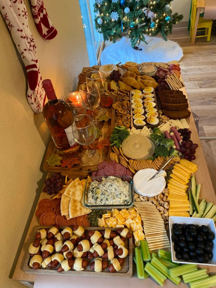 an assortment of appetizers and snacks on a table with christmas tree in the background