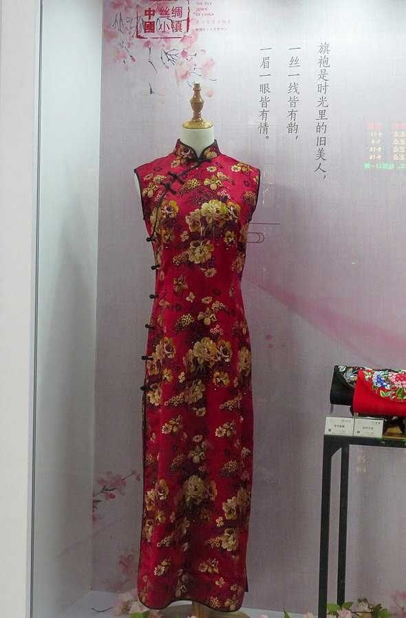 a red dress is on display in a glass case, with chinese writing behind it