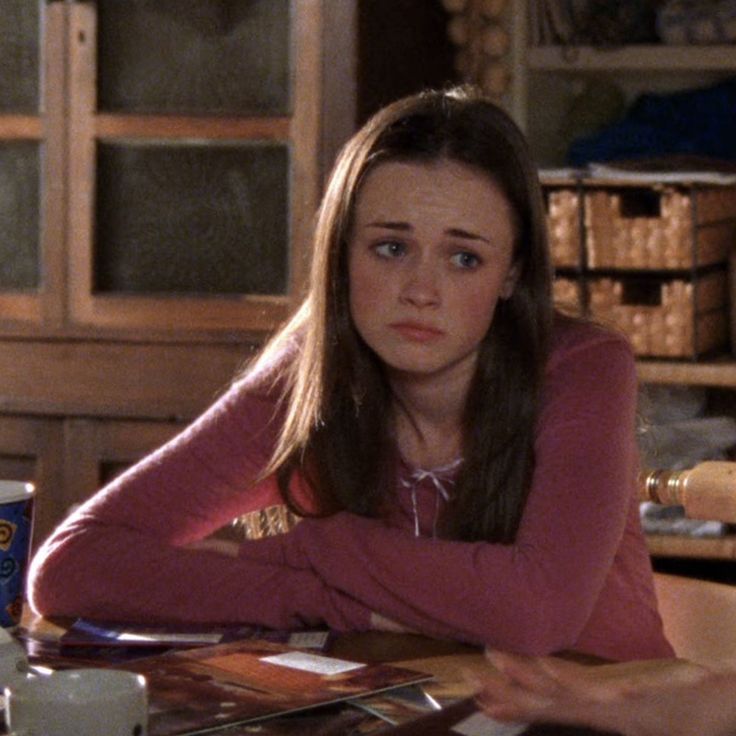 a woman sitting at a table in front of a coffee cup