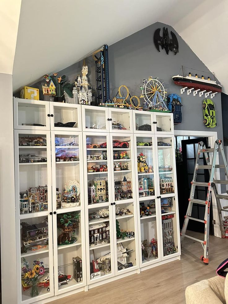 a room filled with lots of toys and shelves next to a ladder on the wall