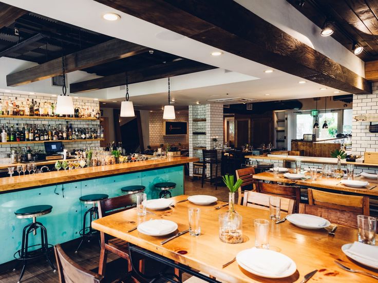 an empty restaurant with wooden tables and bar stools