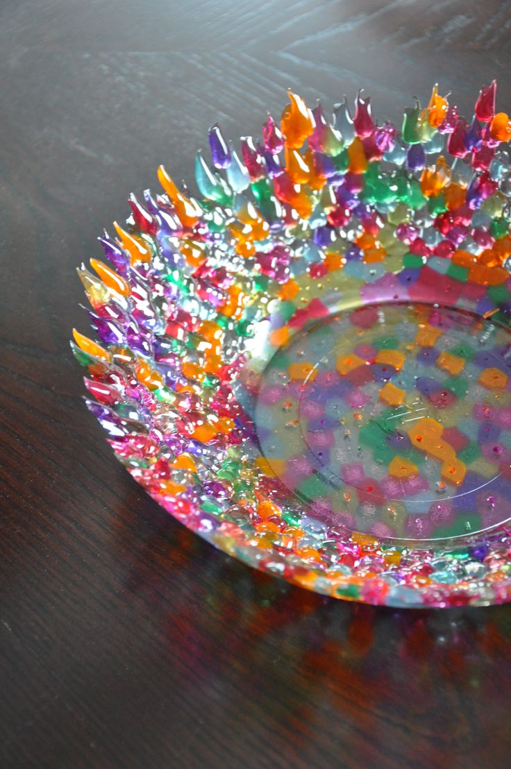 a colorful glass bowl sitting on top of a wooden table covered in confetti