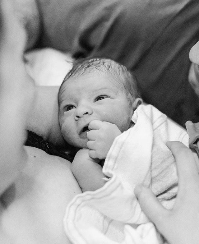 a black and white photo of a baby being held up by someone's hands