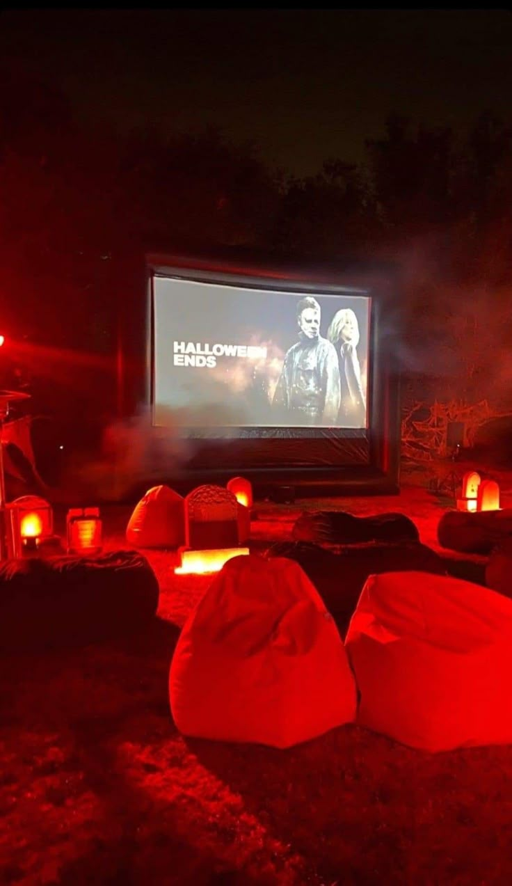 an outdoor movie theater at night with red lights and bean bag chairs in the foreground