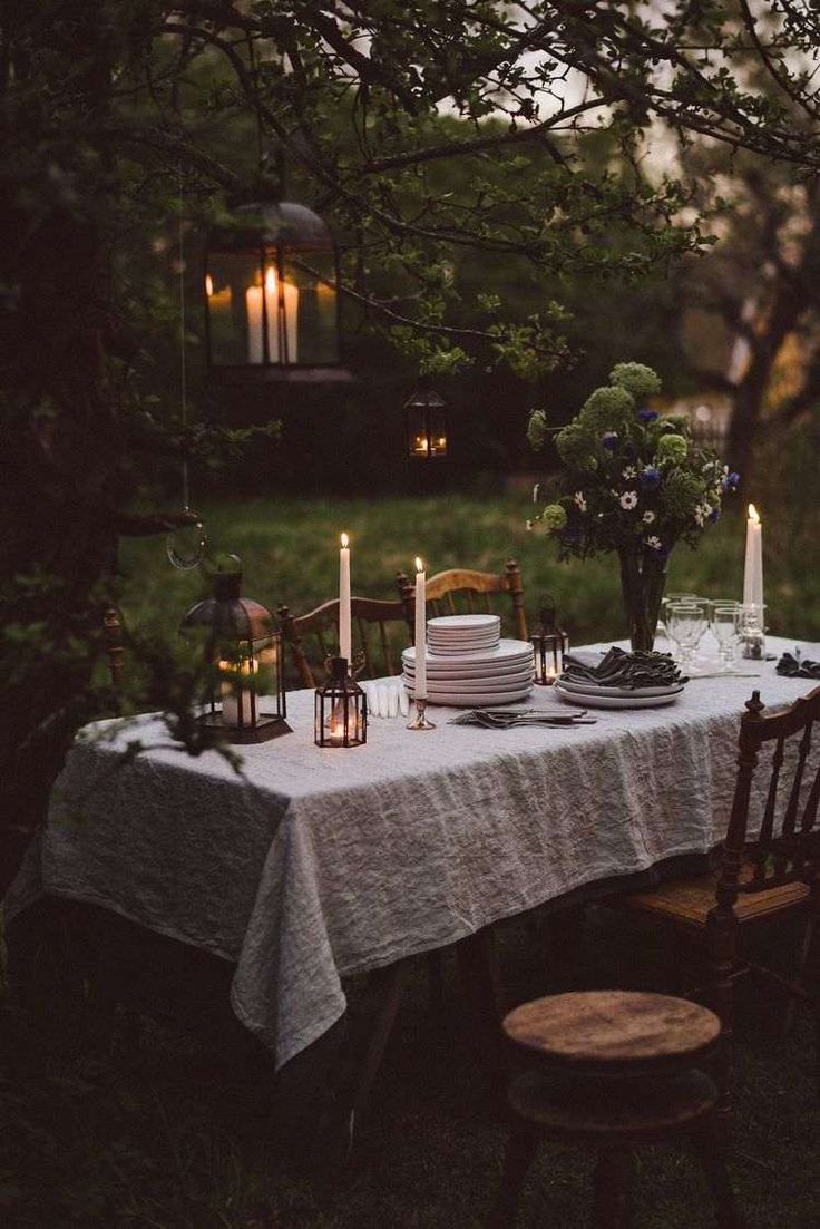 a table with plates and candles on it in the middle of a field at night