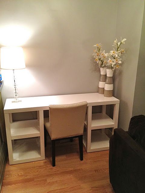 a living room area with a couch, table and chair next to a lamp on the wall