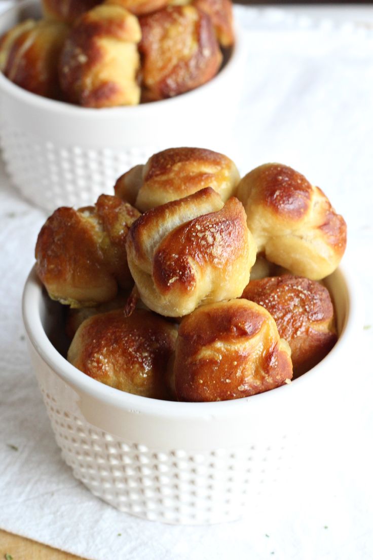 two white bowls filled with cinnamon buns on top of a table