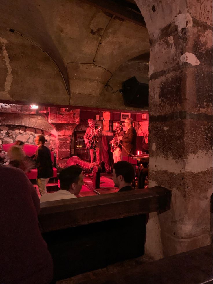 a group of people standing in front of a brick wall with red lights on it