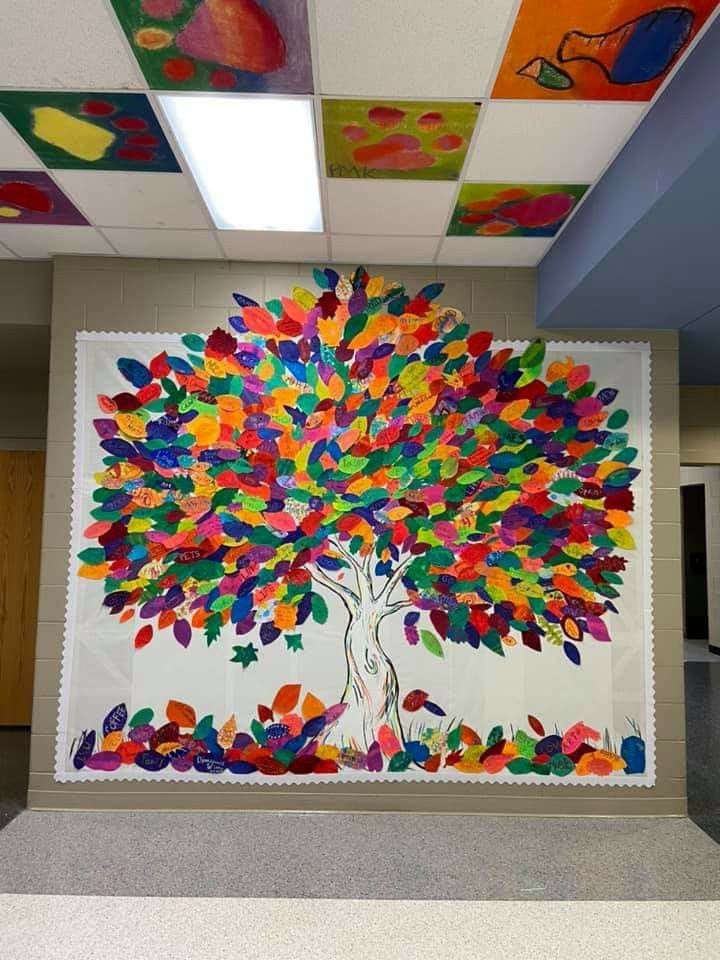 an art work is displayed on the wall in this classroom room with colorful leaves painted on it