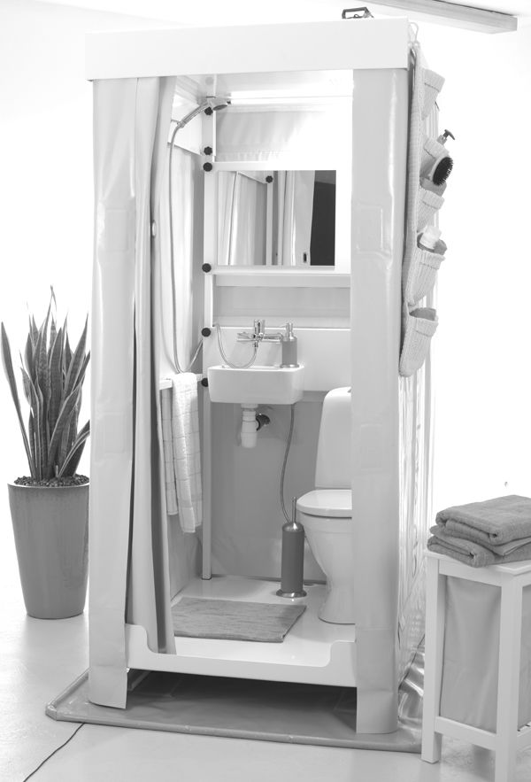 a bathroom with a toilet, sink and shower stall in black and white photo next to a potted plant