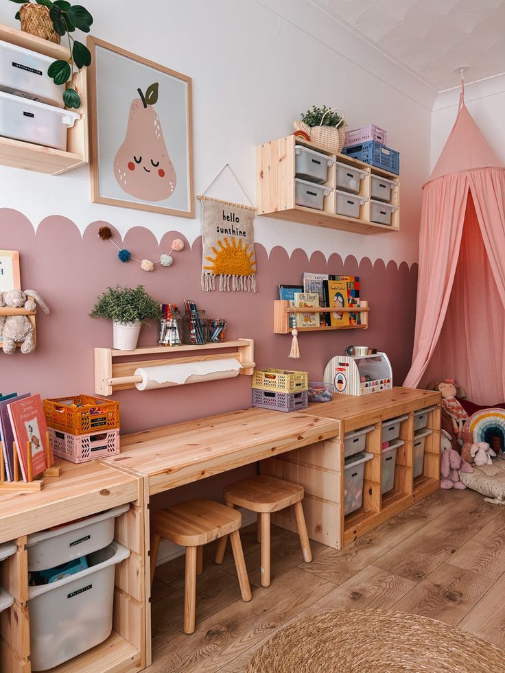 a child's room with pink walls and wooden shelves, toys on the floor