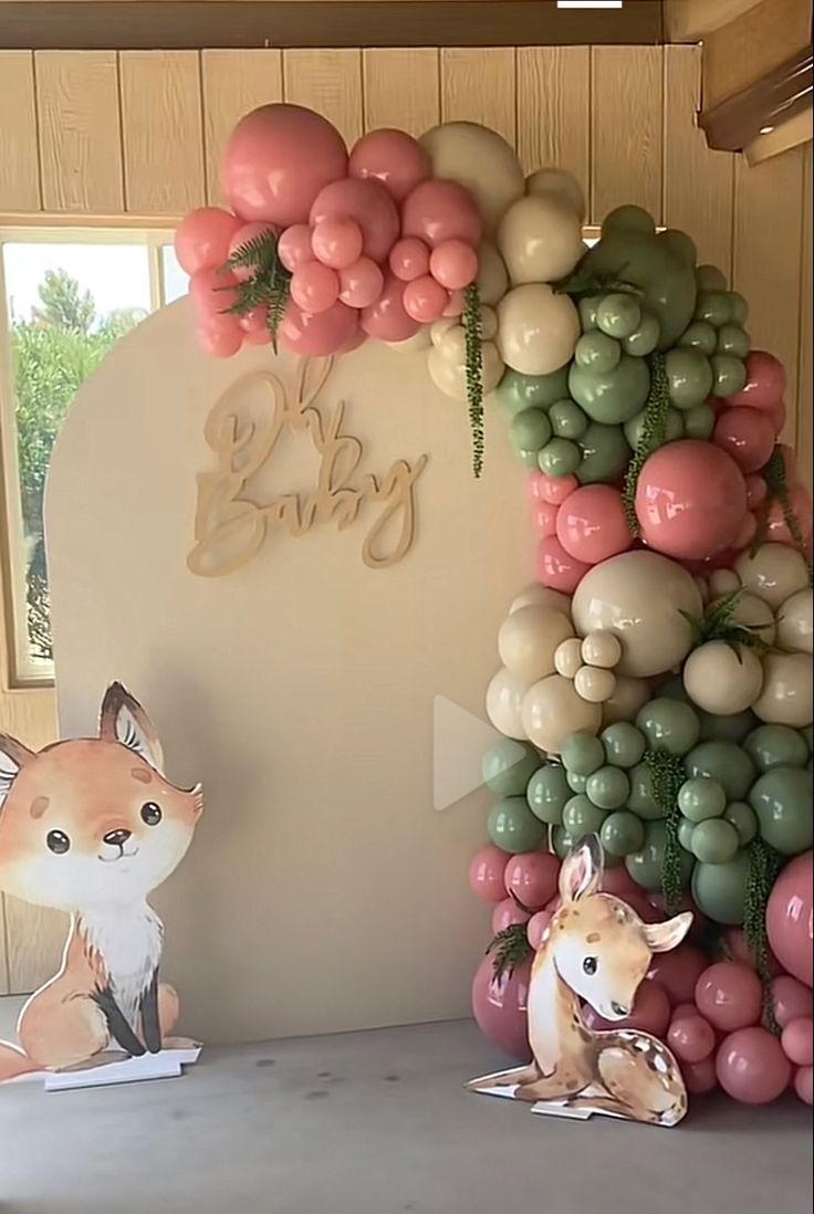 some balloons are hanging on the wall next to a deer and balloon arch that says baby