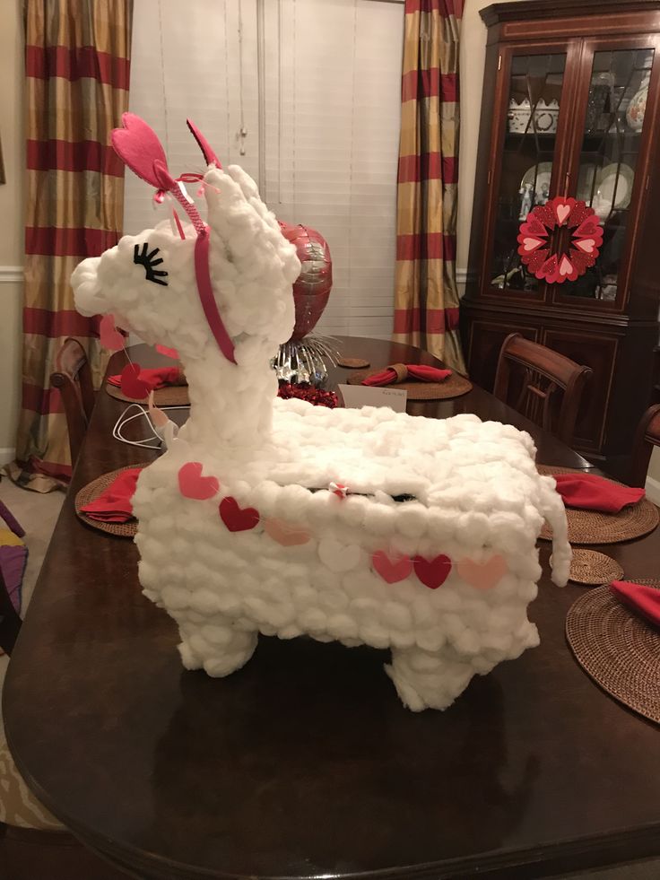 a cake shaped like a llama with hearts on it's tail sitting on top of a table