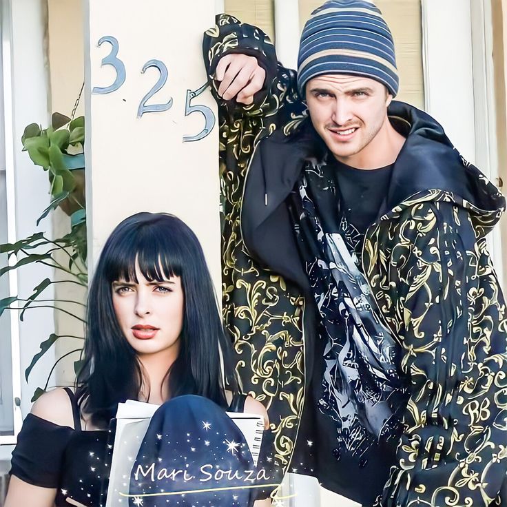 two people standing next to each other in front of a building with a clock on it