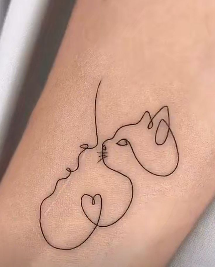 a small tattoo on the leg of a woman with two cats and one cat's head