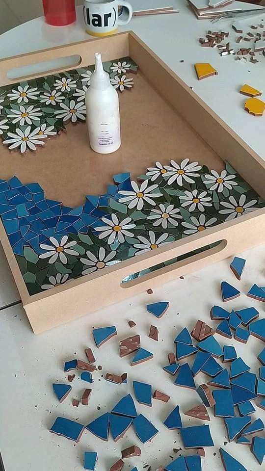 a wooden tray with blue and white mosaic tiles on it next to a bottle of glue