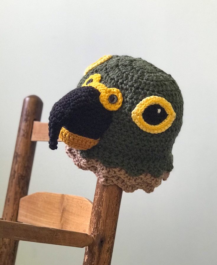 a crocheted bird hat sitting on top of a wooden chair