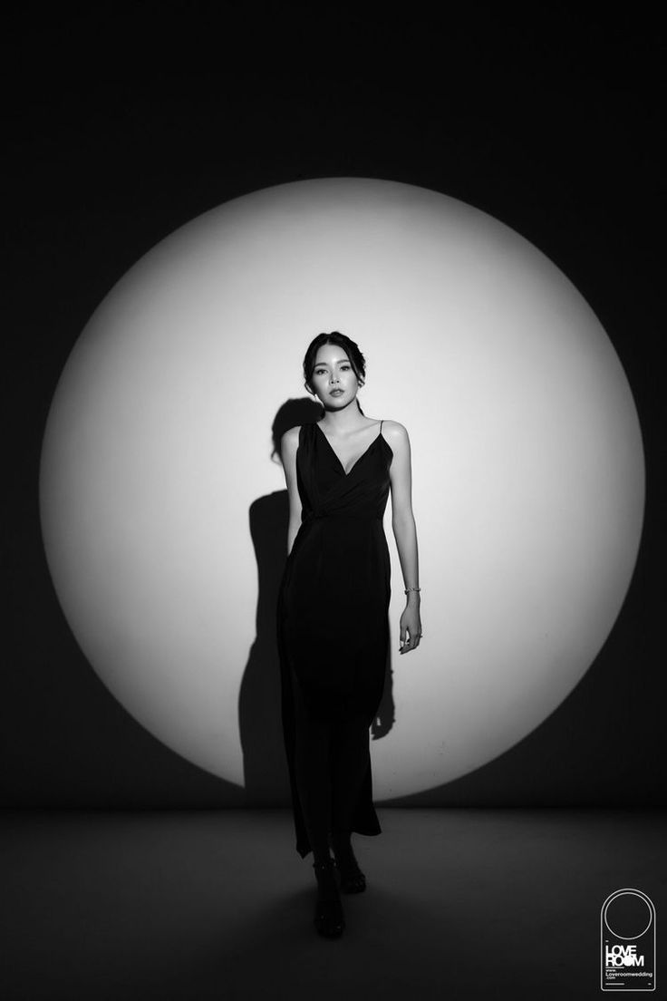 a woman standing in front of a white ball with her shadow on the wall behind her