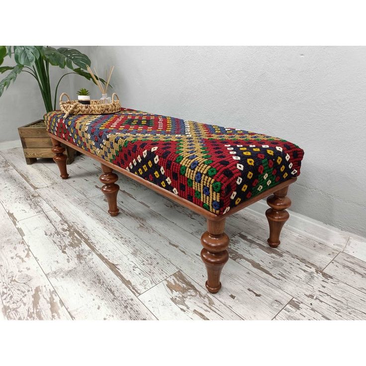 a wooden bench with a multicolored blanket on it's back and legs