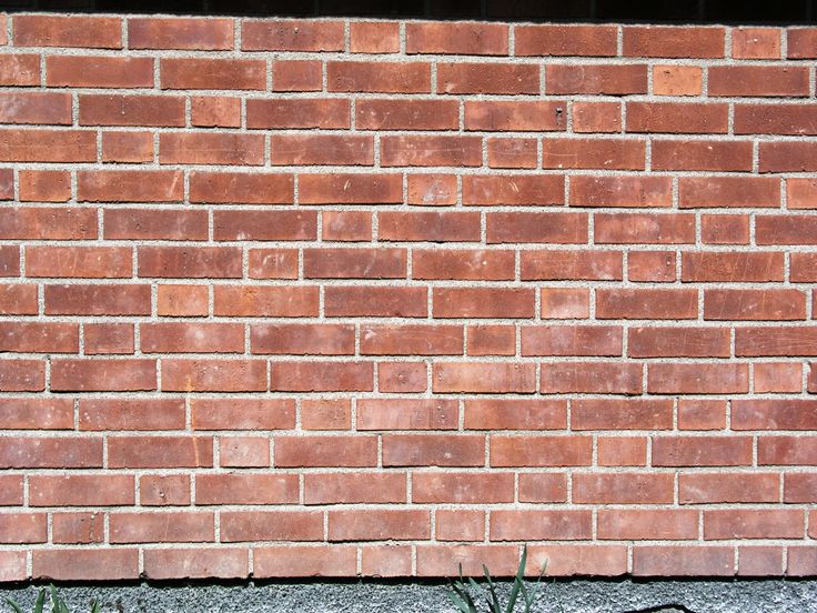 a red brick wall with grass growing in between it and the bottom part of it