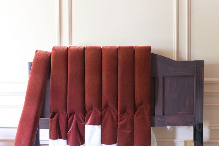 red and white curtains hanging on the side of a wooden headboard in a room