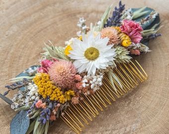 a close up of a comb with flowers and leaves on it sitting on a piece of wood