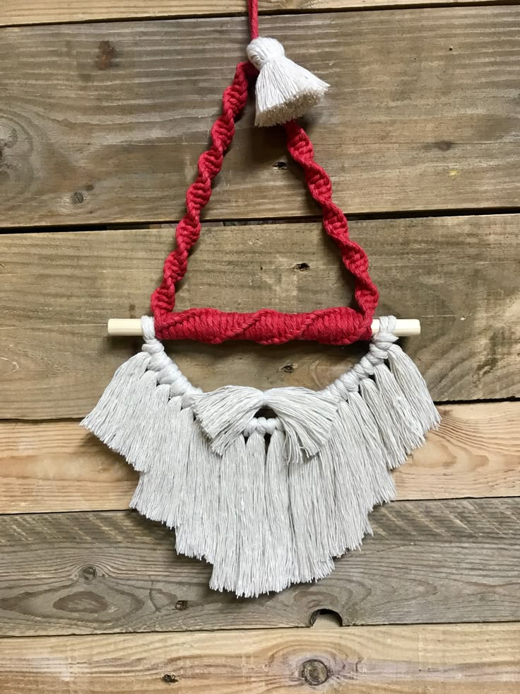 a red and white necklace with tassels hanging from it's side on a wooden wall