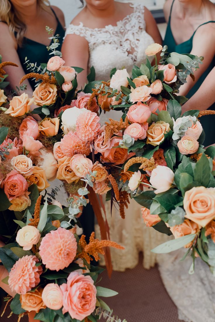 the bridesmaids are holding their bouquets with orange and pink flowers on them