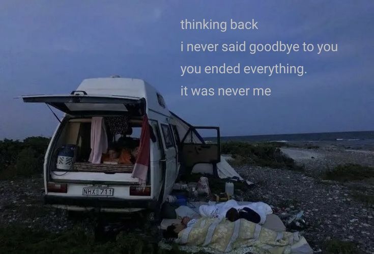 a van parked on the side of a road next to an open field with people sleeping in it