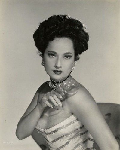 an old black and white photo of a woman holding a glass in her right hand