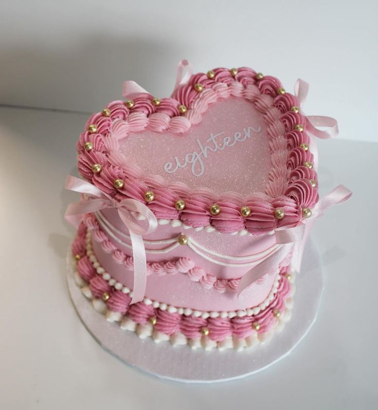 a pink heart shaped cake sitting on top of a table