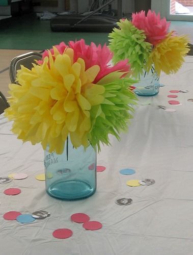 two vases filled with flowers sitting on top of a table covered in confetti