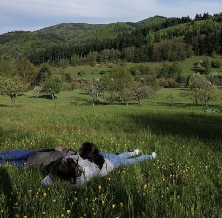 two people laying on the ground in a field