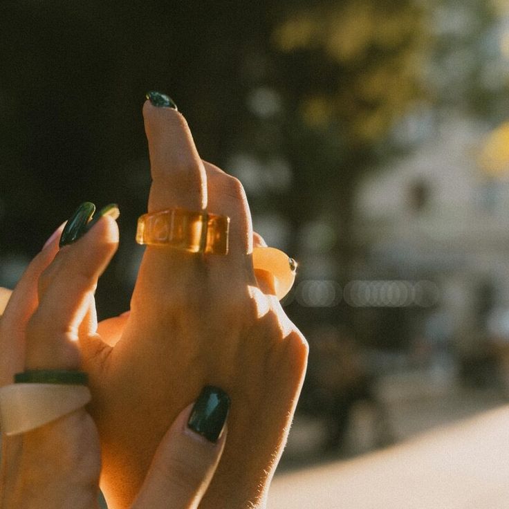 a woman with green nail polish holding up her finger to the camera while wearing a gold ring