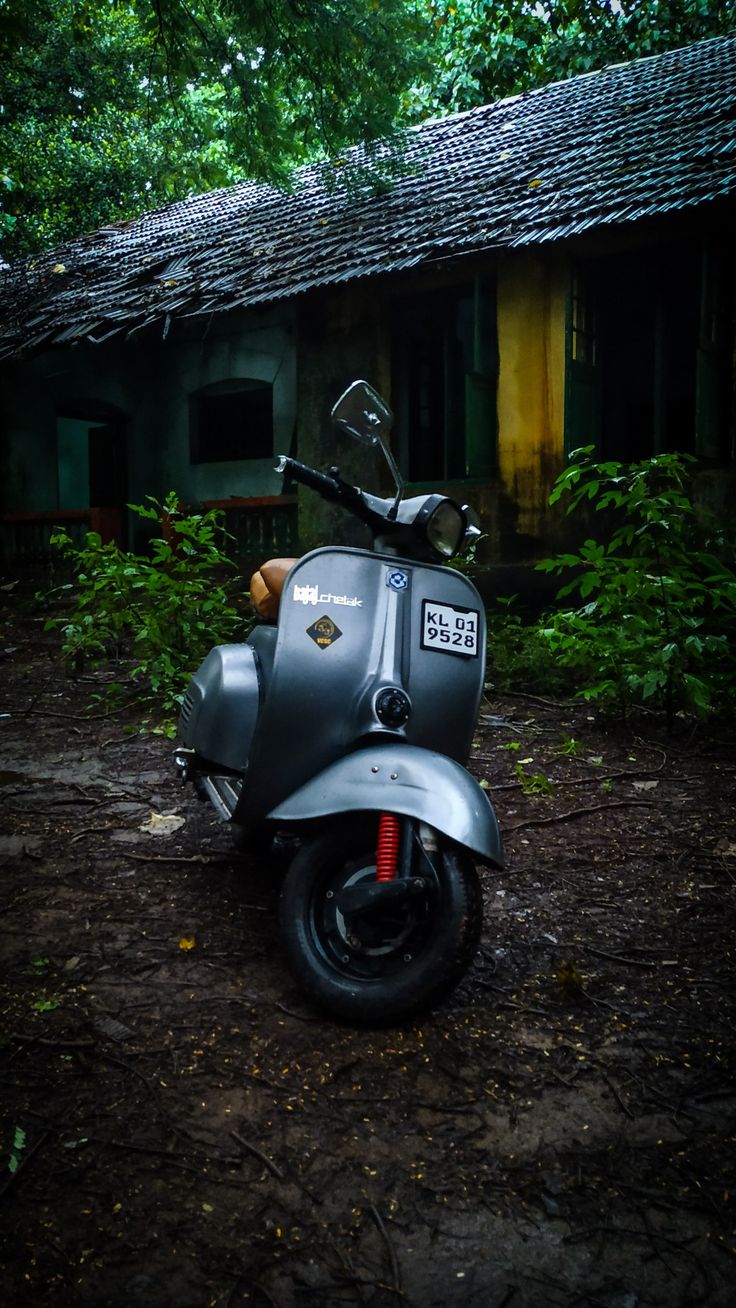 a motor scooter parked in front of a building surrounded by trees and bushes