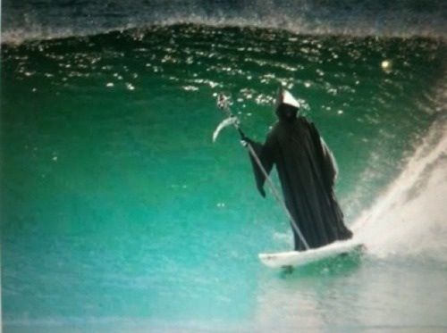 a man on a surfboard in the ocean holding a spear and wearing a cape