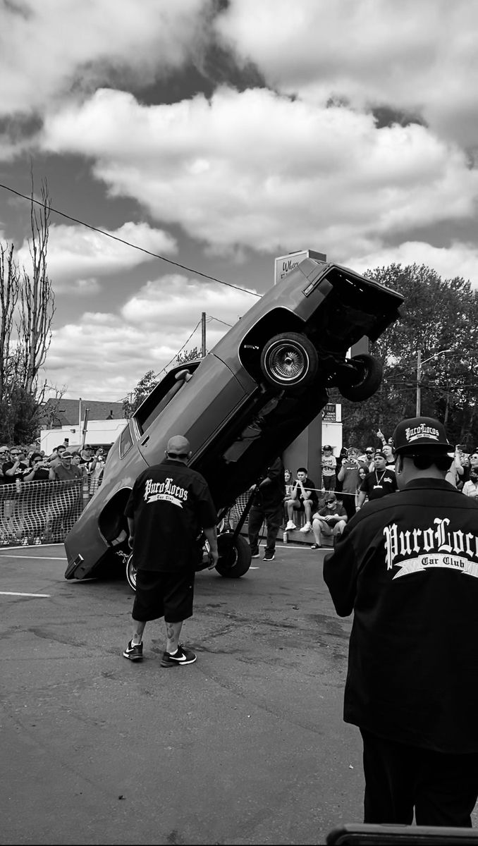 two men standing next to a car that is upside down