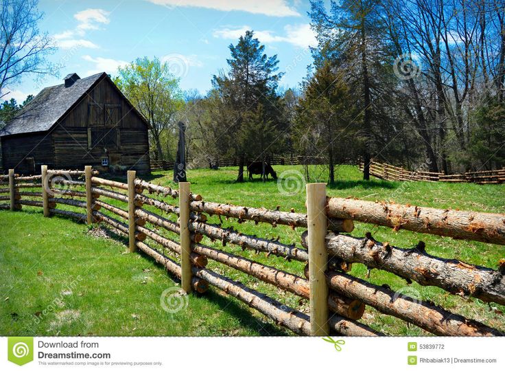 an old log fence in front of a rustic barn