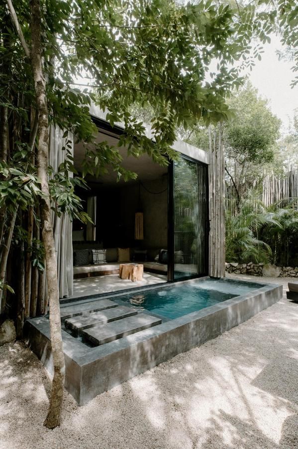 an outdoor hot tub surrounded by trees in the middle of a courtyard with seating area