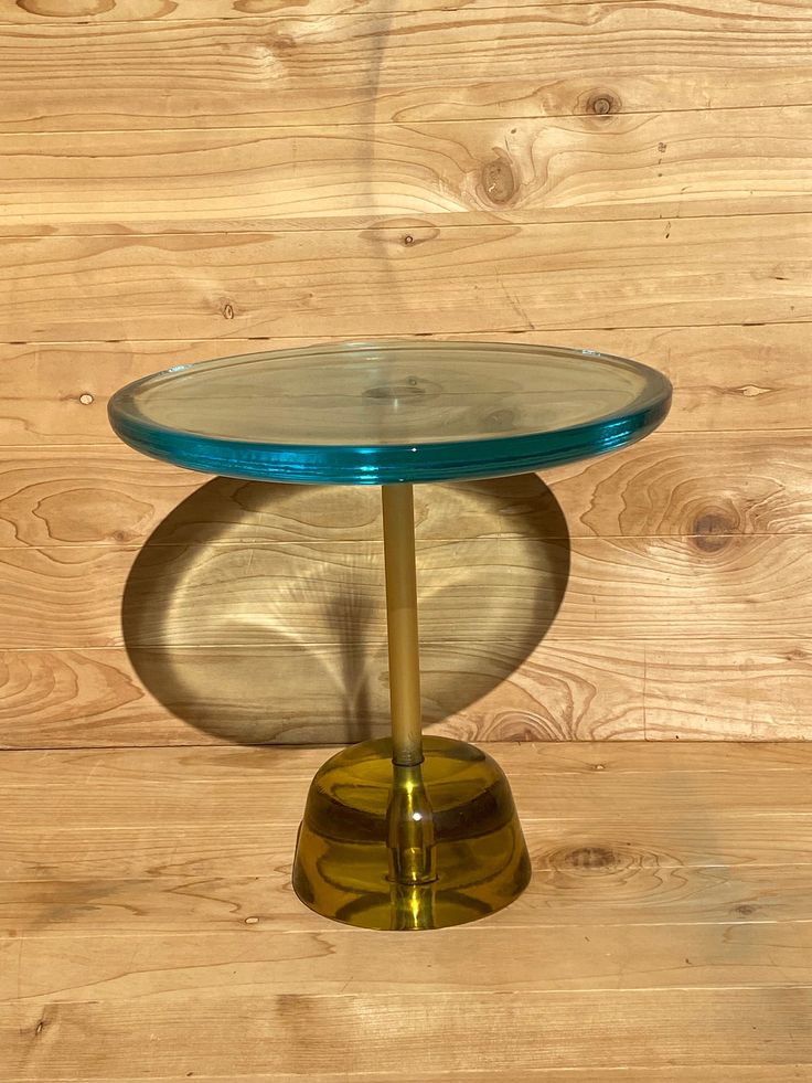 a glass table sitting on top of a wooden floor next to a wood paneled wall